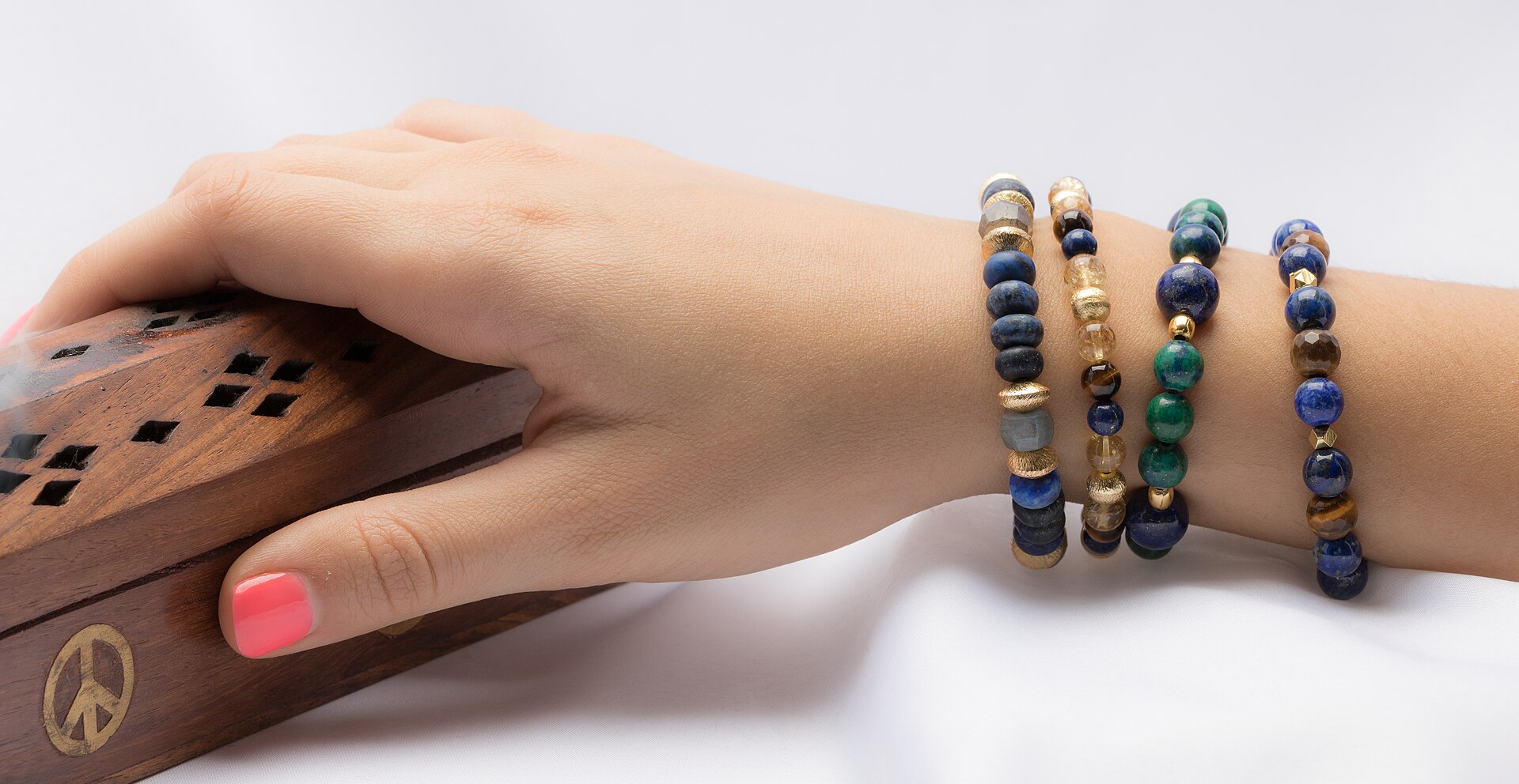 A wrist stacked with natural power-stone bracelets